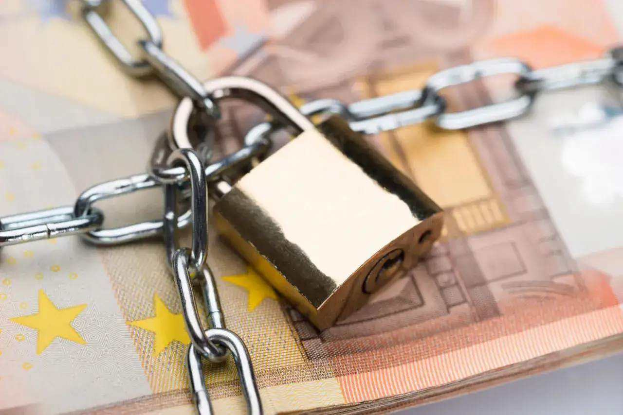 Un cadenas et une chaîne sécurisent des billets en euros, symbolisant la consignation de loyer ou la protection des fonds.