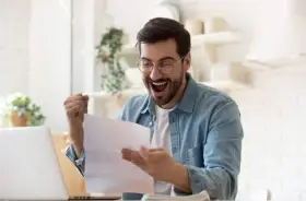 Homme joyeux, poing levé, découvrant une bonne nouvelle sur un document, peut-être la rémunération gérant SCI.
