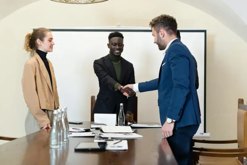 Trois personnes en tenue d'affaires se serrent la main. L'un d'eux discute des intérêts d'un compte séquestre notaire.